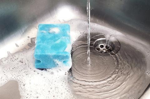 Sponge in kitchen sink under running water