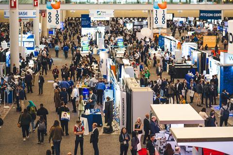 A busy conference exposition floor at Pittcon with attendees moving between stands