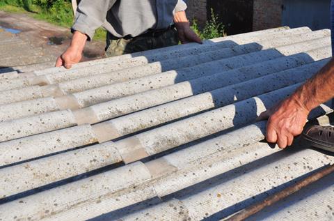 Roofers replace damaged asbestos tile