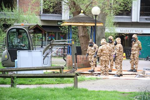 A photo of emergency staff in protective clothing removing a bench from a park