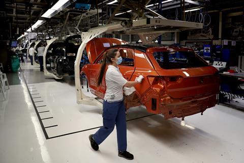 An image showing an employee wearing a face mask works on the production line at the Volkswagen Autoeuropa car factory