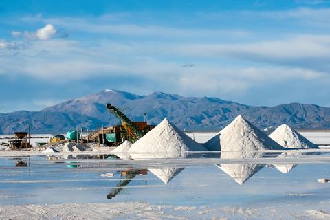 A working lithium mine with piles of salt and a view of the Andes mountain range behind