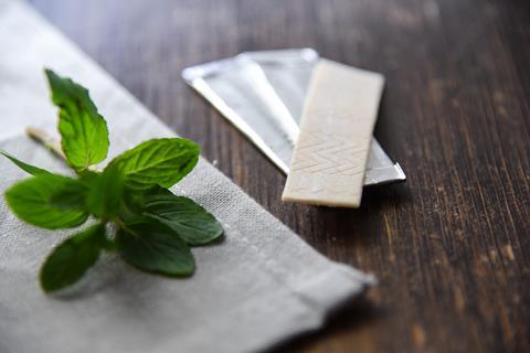 Chewing gum with a mint leaf on a wooden table