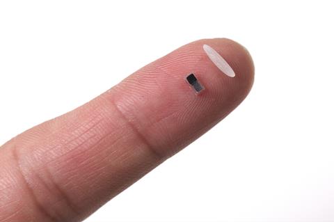 Pacemaker next to a single grain of rice on a fingertip