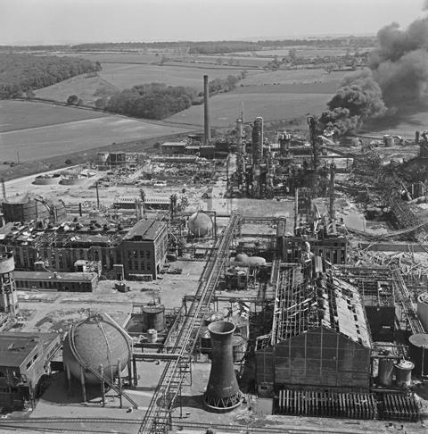Black and white photo of a chemical plant with black smoke billowing from one building