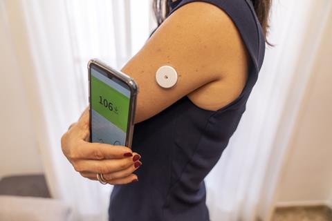 An image showing a woman using smart phone to check her blood sugar levels