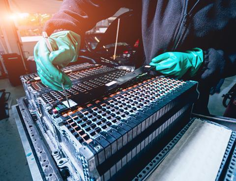 A photo of someone removing the cells of an electric car battery
