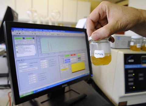 Hand holding jar of honey next to spectrometer