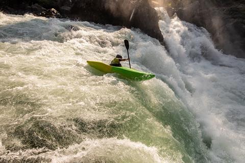 A kayaker in white water going over a waterfall