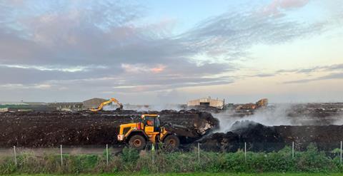 Large piles of compost being turned by a tractor