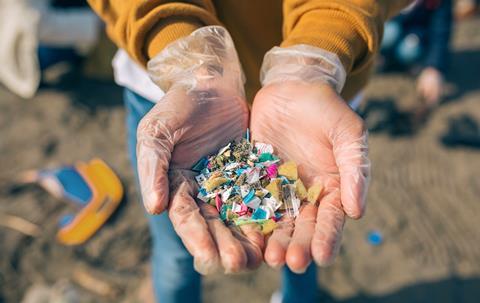 Someone holding small pieces of plastic on a beach