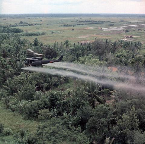 A UH- 1D helicopter from the 336th Aviation Company sprays a agent orange on a dense jungle area in the Mekong delta - Illustration
