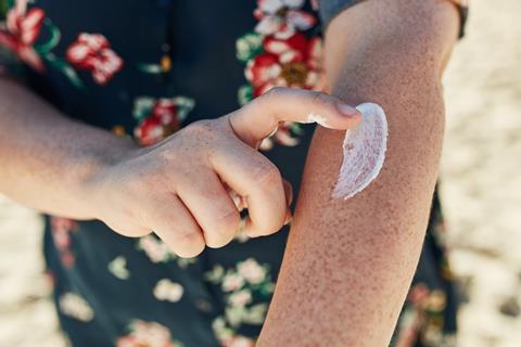 Sunscreen being applied to a fair-skinned arm with freckles