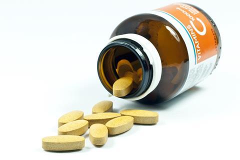 Vitamin C tablets pouring out from bottle onto a table