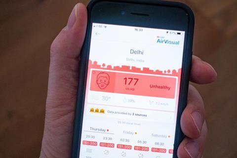 An image showing using a mobile phone to show unhealthy air quality in Delhi