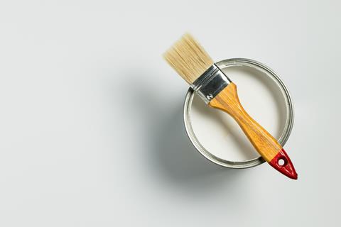 A can of white paint with a paintbrush 