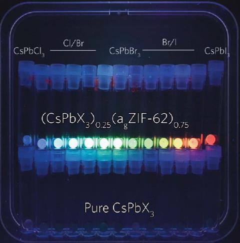 A photo of a three rows of small disks made from a hard material. The disks in the middle row each glow a different colour from blue-green on the left to red on the right.