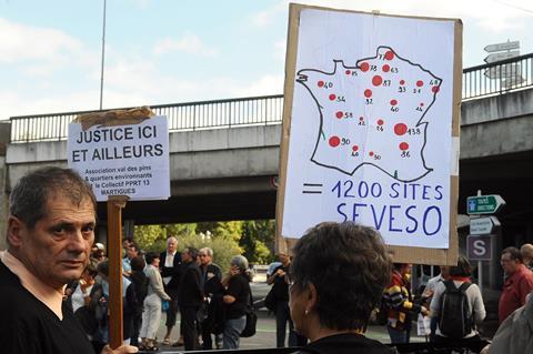 Environmental protestors, one holding a placard with an image of Seveso-like sites on a France map