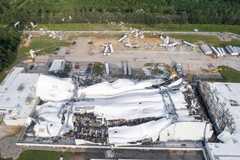 Aerial image of a large white warehouse that has been flattened surrounded by debris and upturned containers