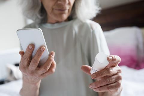 An image showing a woman holding a smartphone and a pack of pills