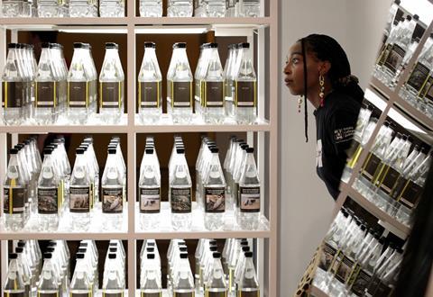 A woman at the Plastic exhibition looking at a shelf filled with rows and rows of plastic bottles