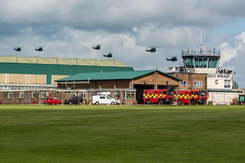 Military helicopters arriving at RAF air base Middle Wallop. In the foreground is the control tower and some fire engines.