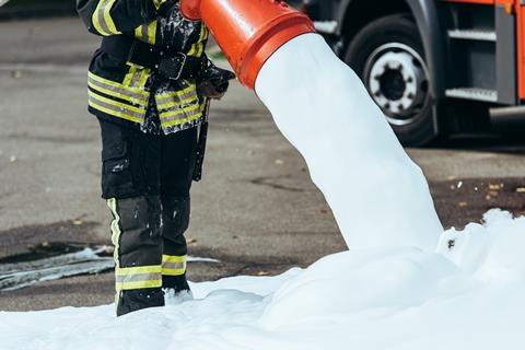 A firefighter spraying foam onto the ground