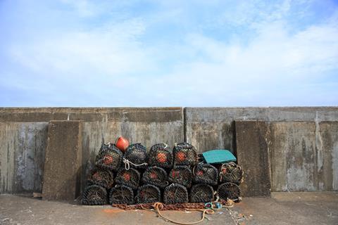 Stack of lobster pots against a sea wall