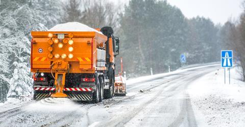 Snow plow on highway salting road