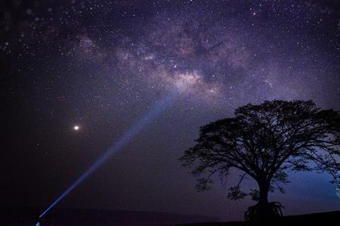 A photo showing the night sky with the Milky Way, Venus and a torch beam