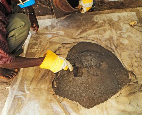 A man prods a pile of coltan ore