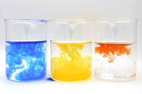Three beakers with coloured encapsulated powders being dispersed in water