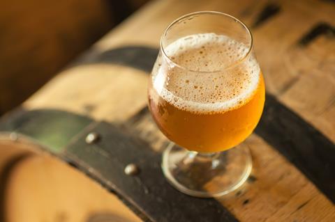 An image showing a glass of beer on top of a barrel